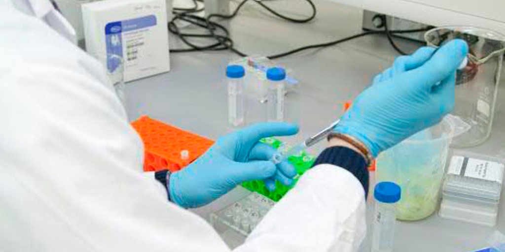 Laboratoriearbeider i mat- og nytelsesmiddelindustrien tar manuelle prosessprøver for analyse i anleggets' laboratorium