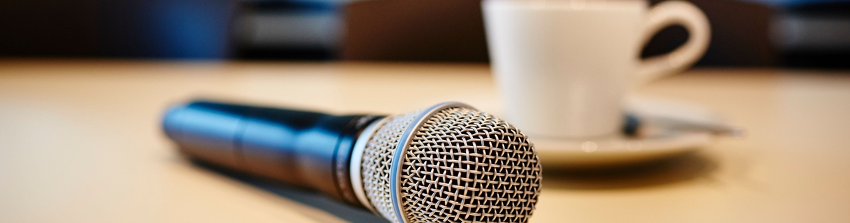 Pressekonferansestemning: mikrofon og kaffekopp på et bord.