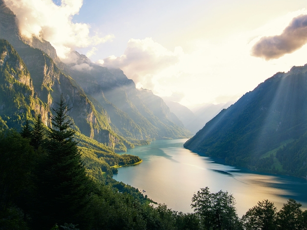 Innsjø omgitt av skogkledde fjell.