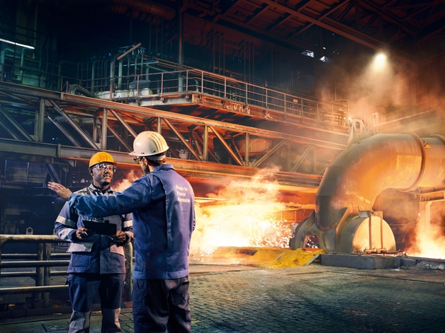 To ingeniører diskuterer på en metallfabrikk.